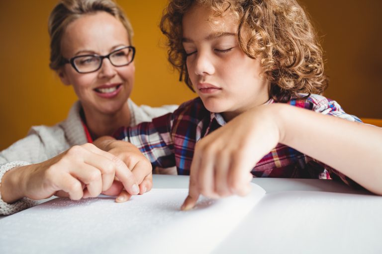 child reading braille with adult